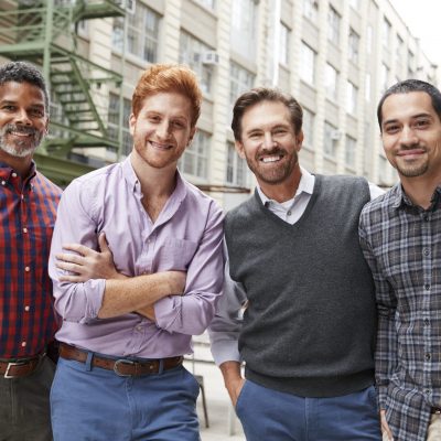 Four male coworkers smiling to camera outside